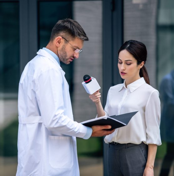 journalist holding microphone and talking with handsome doctor in white coat