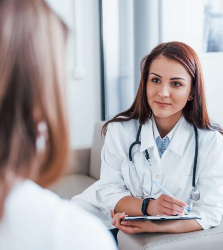 Sitting and talking. Young woman have a visit with female doctor in modern clinic